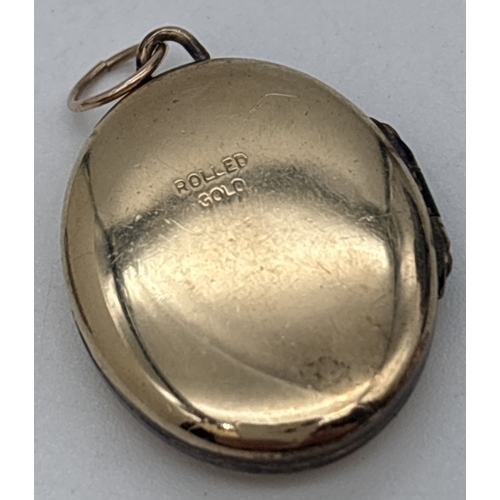 1037 - 2 vintage pendants. A rolled gold oval locket with floral engraved decoration to front, together wit... 