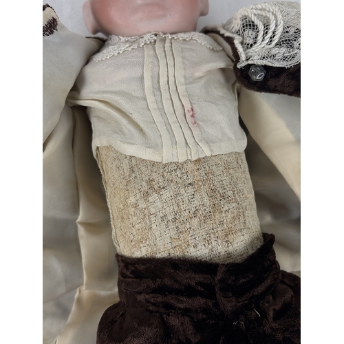 261 - A German Gebruder Knock bisque head boy doll in brown velvet trousers and jacket. Straw filled body ... 