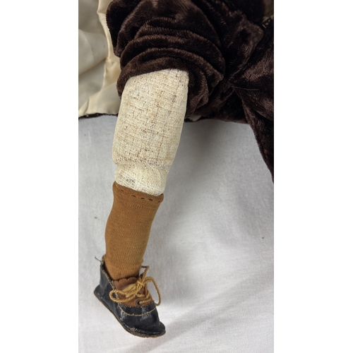 261 - A German Gebruder Knock bisque head boy doll in brown velvet trousers and jacket. Straw filled body ... 