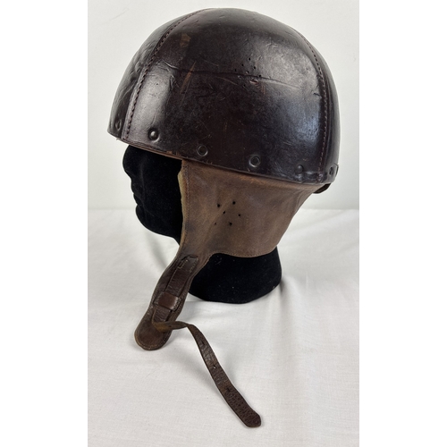 1266 - A World War II era leather pudding basin motorcycle helmet with integral leather neck, ear flaps and... 