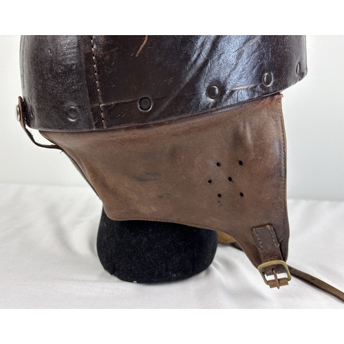 1266 - A World War II era leather pudding basin motorcycle helmet with integral leather neck, ear flaps and... 