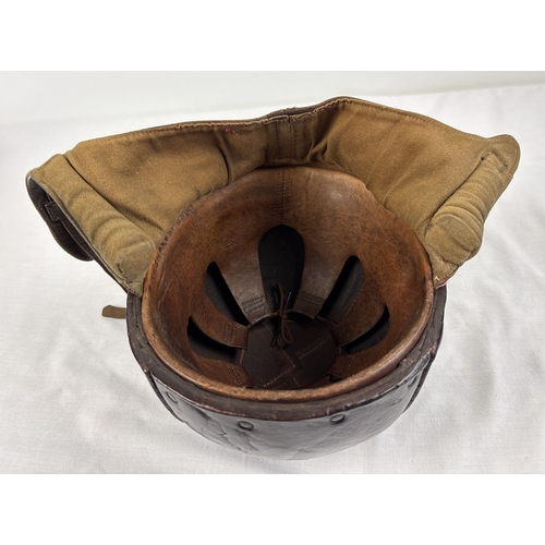 1266 - A World War II era leather pudding basin motorcycle helmet with integral leather neck, ear flaps and... 