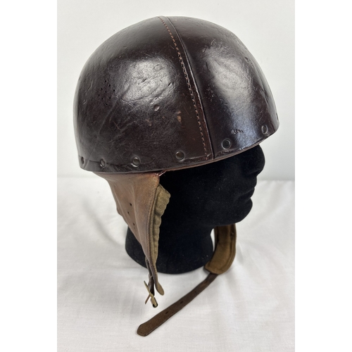 A World War II era leather pudding basin motorcycle helmet with integral leather neck, ear flaps and strap. Stamped inside JHLtd 1942.