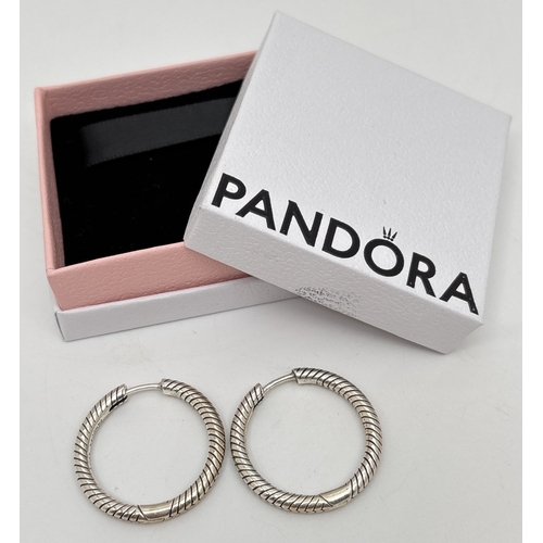 A boxed pair of silver Pandora Moments medium charm hoop earrings. Each stamped Pandora S925 Ale. Approx. 2.5cm diameter. Still current.