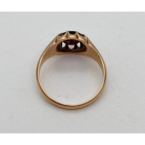 1011 - A vintage 9ct gold men's signet ring set with an oval cut garnet. Scallop edges to mount with split ... 