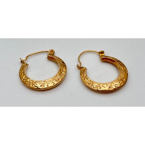 1010 - A pair of yellow gold gypsy style hoop earrings with floral decoration. Unmarked but tests as 9ct go... 