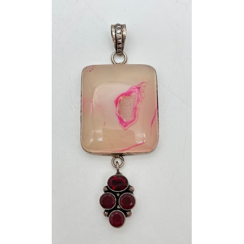 1041 - A large silver modern design pendant set with four round & oval cut garnets, suspended from a large ... 