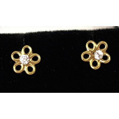 1053 - A pair of yellow gold flower head design stud earrings, each set with a clear CZ stone. Earrings unm... 