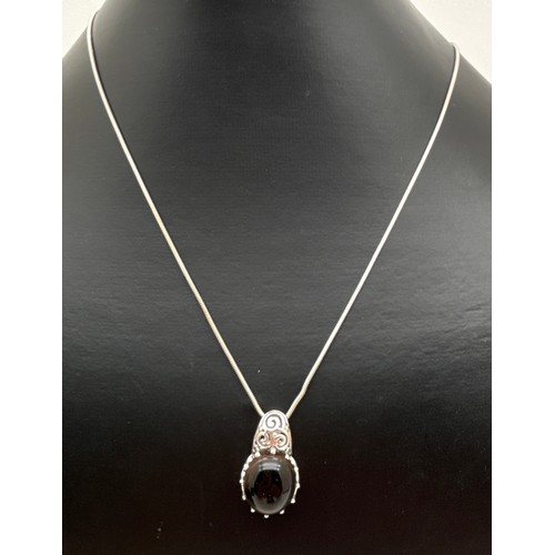 1056 - A boxed silver pendant set with an oval smoked quartz cabochon with claw mount and pierced scroll wo... 