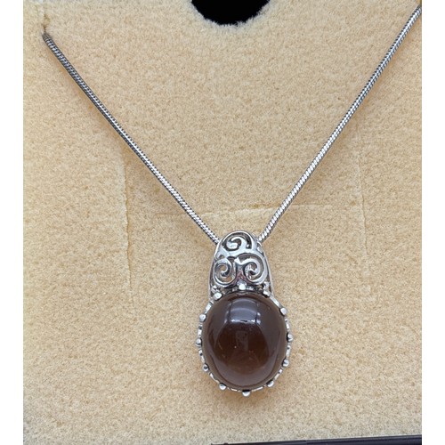 1056 - A boxed silver pendant set with an oval smoked quartz cabochon with claw mount and pierced scroll wo... 