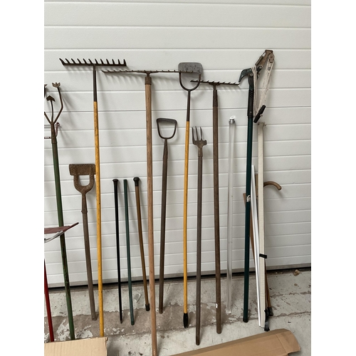 128 - LARGE SELECTION OF GARDEN TOOLS TO INCLUDE RAKES, HOES ETC