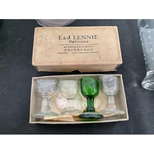 43 - BOX OF VINTAGE EYE WASH GLASSES IN ORIGINAL BOX , MEASURING BEAKERS AND 2 GLASS FLOATS