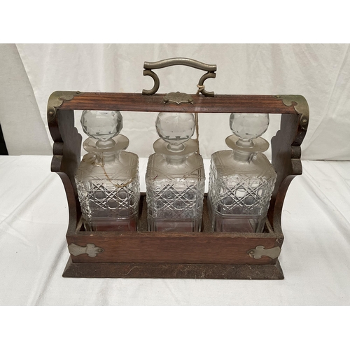 134 - ANTIQUE OAK TANTALUS WITH 3 CUT GLASS BOTTLES (1 A/F) WITH PLATED FITTINGS AND KEY H11