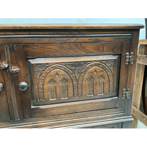 327 - DARK OAK PRIORY STYLE TWO DOOR CABINET WITH CARVED PANELS SHAPED FREEZE ON STRETCHERED BASE H33