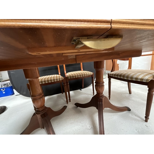 384 - REPRODUCTION REGENCY STYLE MAHOGANY TWIN PEDESTAL DINING TABLE WITH EXTRA LEAF AND 6 MATCHING CHAIRS... 