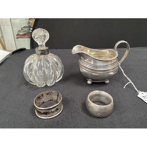 205 - HALLMARK SILVER CREAM JUG, 2 NAPKIN RINGS, COLLARED SCENT BOTTLE 
APPROX TOTAL WEIGHT 155G