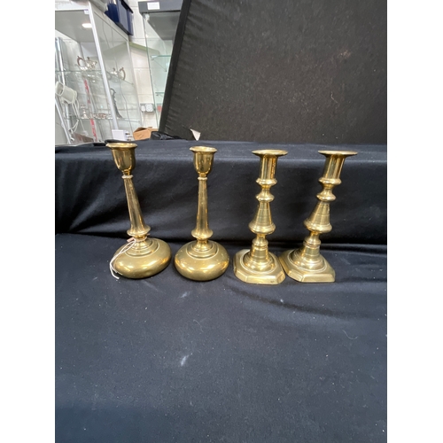 42 - TWO PAIRS OF BRASS CANDLE STICKS AND A PAIR OF EMBOSSED PLAQUES