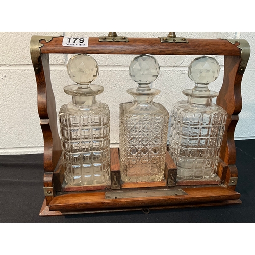 179 - VICTORIAN OAK 3 BOTTLE TANTALUS WITH KEY - DECANTERS ARE A/F