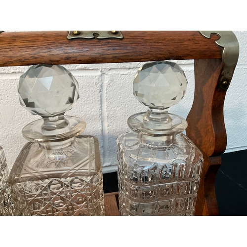 179 - VICTORIAN OAK 3 BOTTLE TANTALUS WITH KEY - DECANTERS ARE A/F