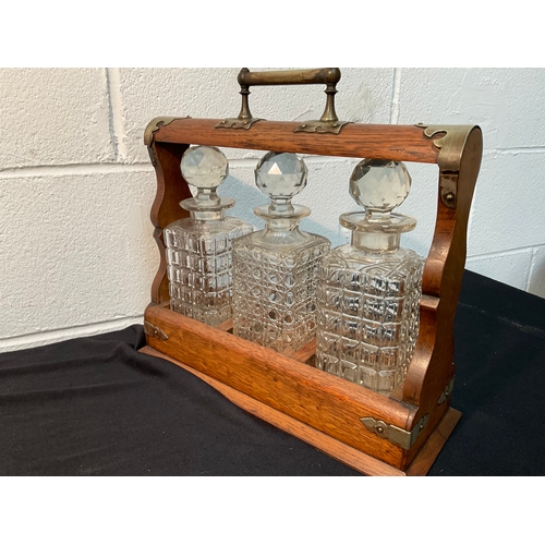 179 - VICTORIAN OAK 3 BOTTLE TANTALUS WITH KEY - DECANTERS ARE A/F