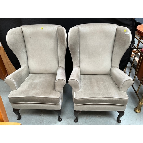 397 - TWO GREEN UPHOLSTERED WINGBACK FIRESIDE CHAIRS ON FRONT CABRIOLE FEET.