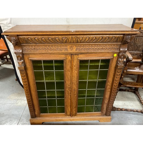 429 - EDWARDIAN CARVED OAK GOTHIC STYLE TWO DOOR BOOK CASE WITH GREEN GLASS PANELS W46