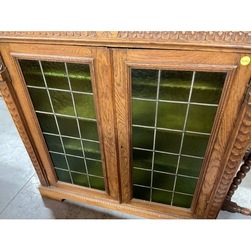 429 - EDWARDIAN CARVED OAK GOTHIC STYLE TWO DOOR BOOK CASE WITH GREEN GLASS PANELS W46