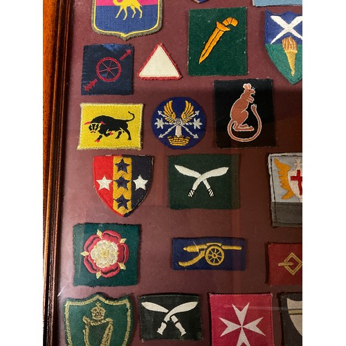 135 - FRAMED COLLECTION OF MILITARY CLOTH PATCHES 26” X 18”