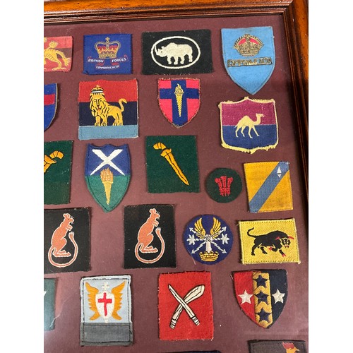 135 - FRAMED COLLECTION OF MILITARY CLOTH PATCHES 26” X 18”