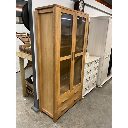 357 - MODERN TWO DOOR GLAZED OAK DISPLAY CABINET WITH TWO DRAWERS TO BASE W36