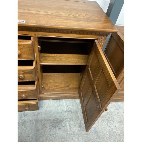 394 - VINTAGE BADGED ERCOL SIDE BOARD FOUR CENTRAL DRAWERS AND CUPBOARD TO EACH END W57