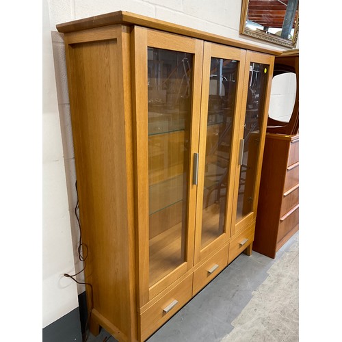 405 - MODERN GOLDEN OAK THREE DOOR GLAZED DISPLAY CABINET WITH THREE DRAWERS TO BASE W50