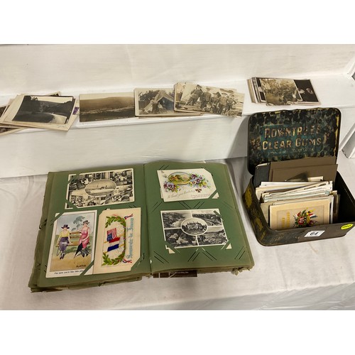 64 - POSTCARD ALBUM AND TIN OF POSTCARDS TO INCLUDE VARIOUS SUBJECTS TO INCLUDE THE WAR, SHIPS RAILWAY, V... 