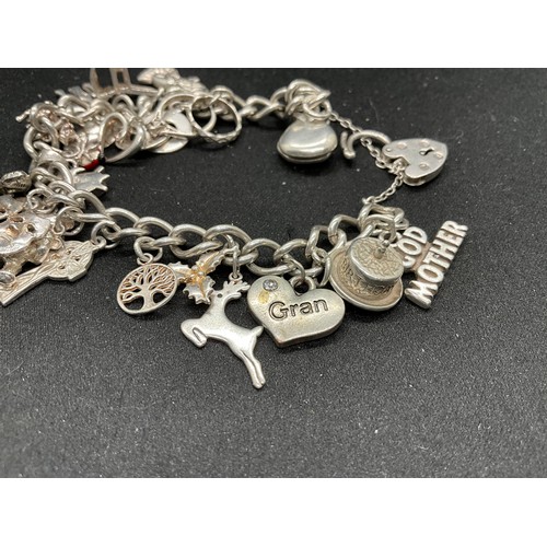 43 - SILVER CHARM BRACELET (TESTED) WITH 24 SILVER CHARMS TW54G 2 CHARMS HELD IN PLACE WITH PLATED HOOPS ... 