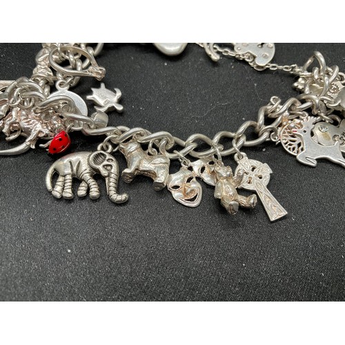 43 - SILVER CHARM BRACELET (TESTED) WITH 24 SILVER CHARMS TW54G 2 CHARMS HELD IN PLACE WITH PLATED HOOPS ... 