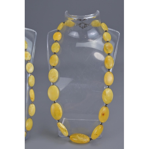 328 - Two flat beaded amber necklaces with white metal spacers and clasp. bead sizes approx.. 20mm - 35mm ... 