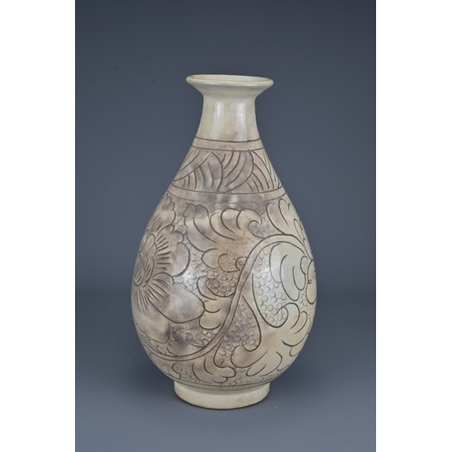 39 - A Chinese Cizhou-type pear-shaped vase. The vase with carved decoration of scrolling peonies. Height... 