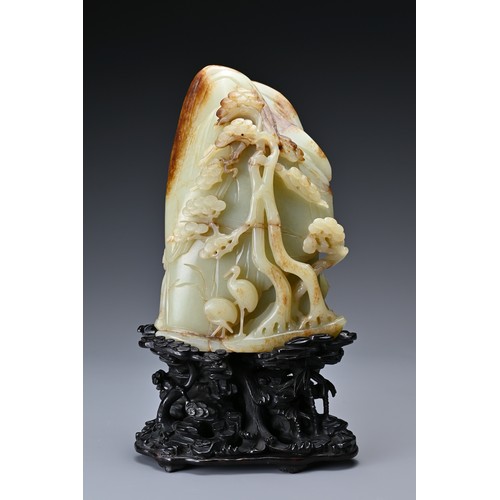 66 - A large Chinese celadon and russet jade boulder. Carved in high relief with two cranes and pine tree... 