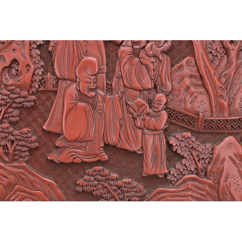 6 - A CHINESE CINNABAR LACQUER PANEL, 19TH CENTURY. Well carved in relief with scholar figures in a land... 