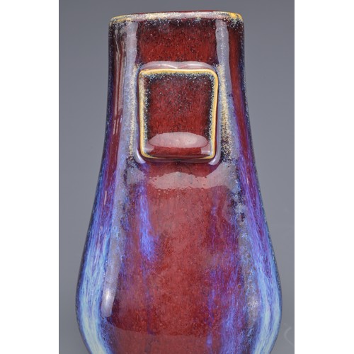 15 - A CHINESE FLAMBE GLAZED HU VASE. With flat rectangular handles covered in a reddish purple glaze wit... 