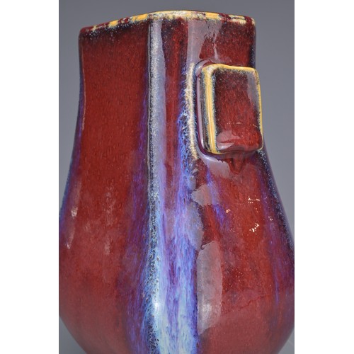 15 - A CHINESE FLAMBE GLAZED HU VASE. With flat rectangular handles covered in a reddish purple glaze wit... 