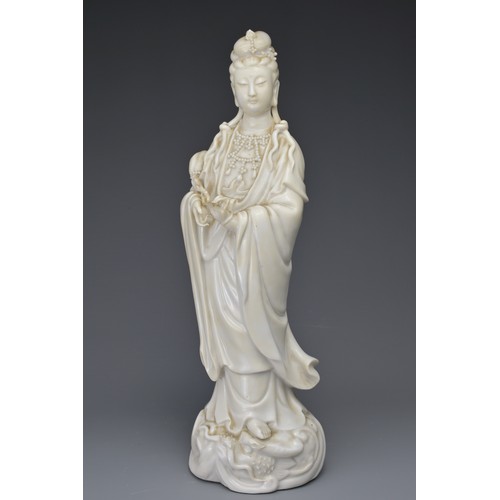 29 - A CHINESE BLANC DE CHINE FIGURE OF GUANYIN. The moulded figure of Guanyin standing on a dragon cover... 