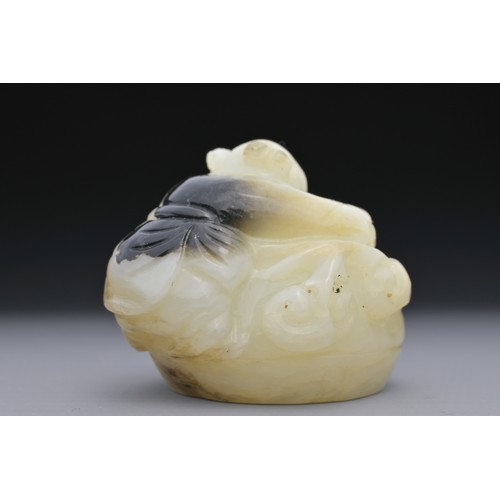 56 - A CHINESE GREENISH-WHITE AND BLACK JADE CARVING OF BOY ON DRUM. The boy lent over a drum with lingzh... 