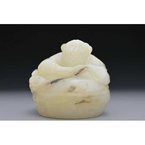 56 - A CHINESE GREENISH-WHITE AND BLACK JADE CARVING OF BOY ON DRUM. The boy lent over a drum with lingzh... 