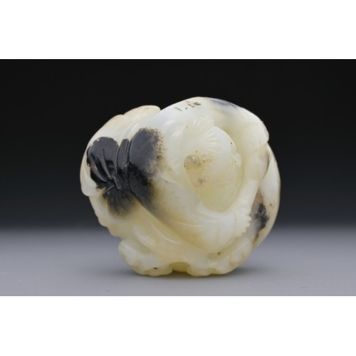 56 - A CHINESE GREENISH-WHITE AND BLACK JADE CARVING OF BOY ON DRUM. The boy lent over a drum with lingzh... 