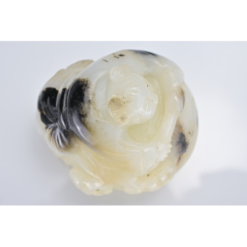 56 - A CHINESE GREENISH-WHITE AND BLACK JADE CARVING OF BOY ON DRUM. The boy lent over a drum with lingzh... 