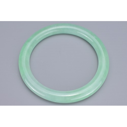 59 - A CHINESE JADEITE CYLINDRICAL BANGLE. Outer diameter 8.7cm. Inner diameter 6.7cm. Thickness approx. ... 