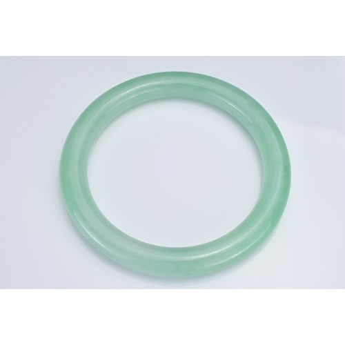 59 - A CHINESE JADEITE CYLINDRICAL BANGLE. Outer diameter 8.7cm. Inner diameter 6.7cm. Thickness approx. ... 