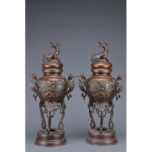 62 - A PAIR OF JAPANESE BRONZE LIDDED URNS. Each with ornate legs and dragon form handles with raised flo... 