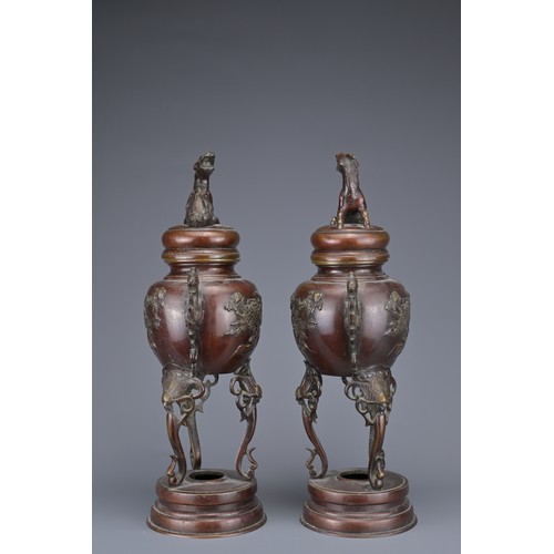 62 - A PAIR OF JAPANESE BRONZE LIDDED URNS. Each with ornate legs and dragon form handles with raised flo... 